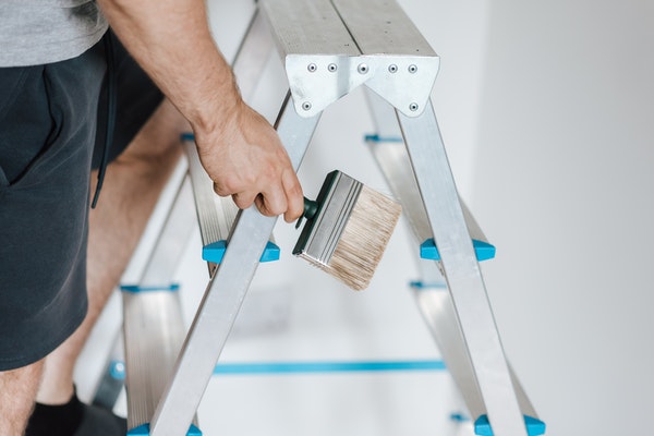 builder on ladder holding paintbrush