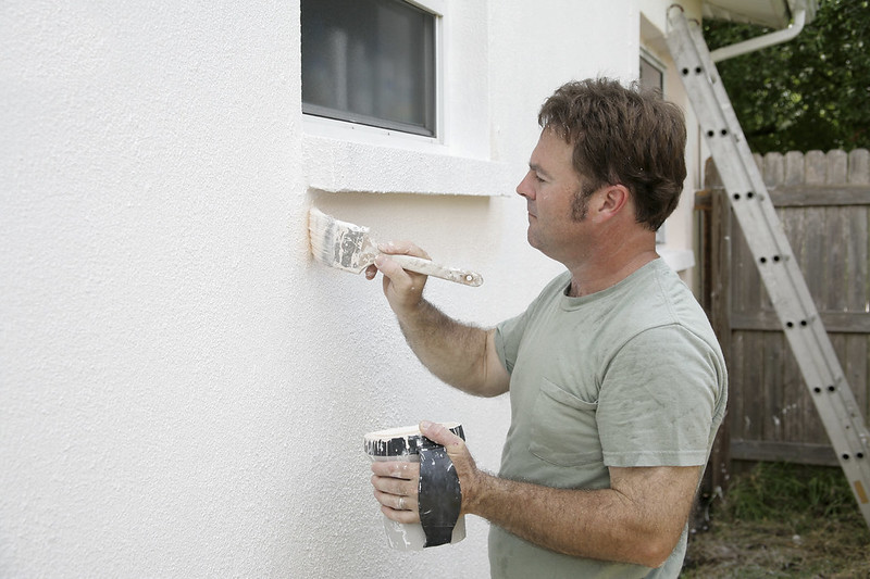 Man painting house with ladder in the background