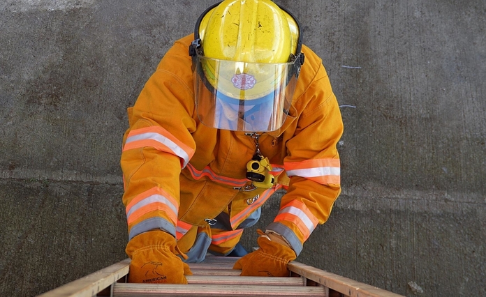 fire fighter in protective gear climbing a ladder