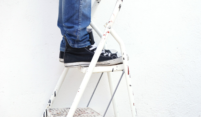 person stood on white metal platform step ladder - using ladders in the workplace