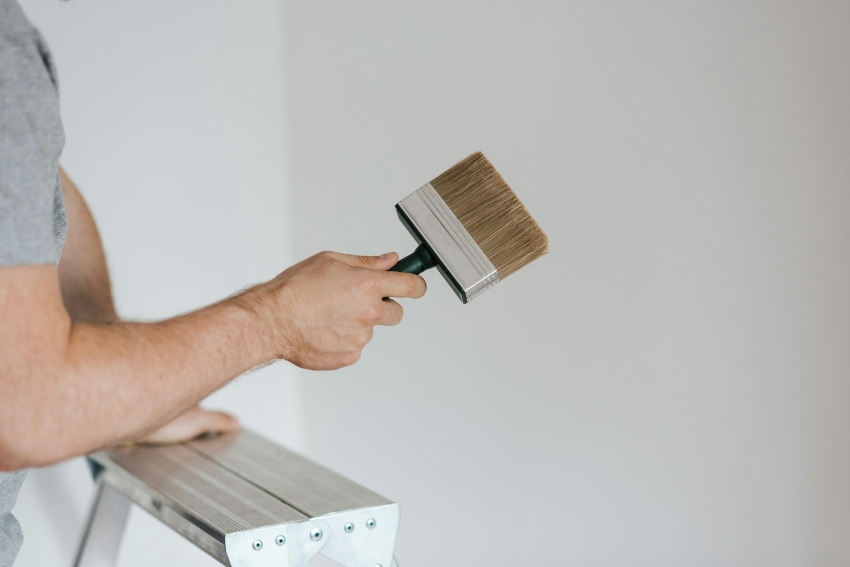 person on step ladder holding a paintbrush