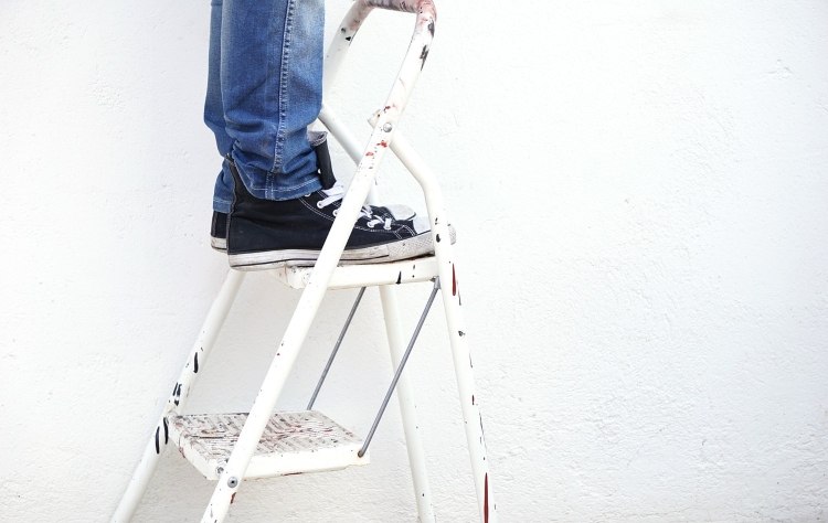 person in jeans standing on a white step ladder - why is my ladder wobbly?