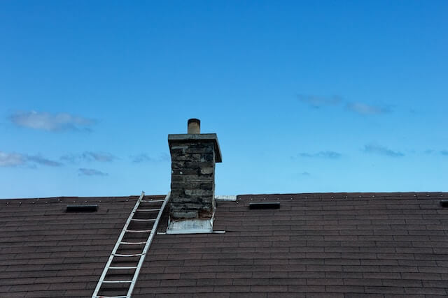 roof ladder hooked over roof next to chimney - Can I Use a Step Ladder to Access My Roof?